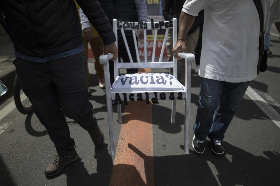 Protesters carry an empty chair that symbolizes Bogota Mayor of Bogota Claudia Lopez's absence in negotiations regarding a city-wide curfew amid the COVID-19 pandemic in Bogota, Colombia, Wednesday, Jan. 20, 2021, as they march toward her residence to demand it be lifted and businesses reopen. (AP Photo/Ivan Valencia)