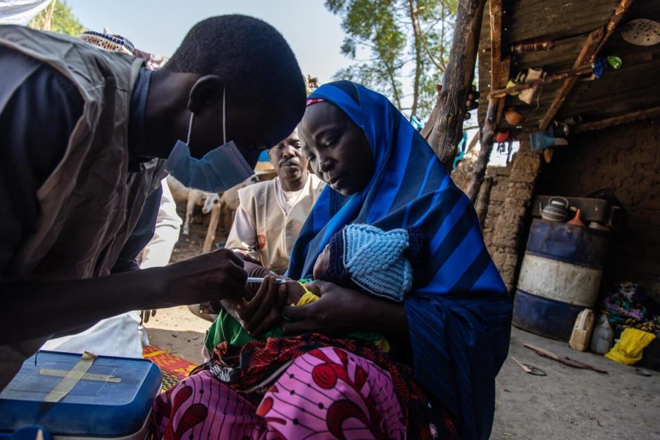 Healthworker Nura Ibrahim administers a vaccine to 22-day-old Rukayya outside his home in Jigawa state (Yagazie Emnezi/Save The Children)