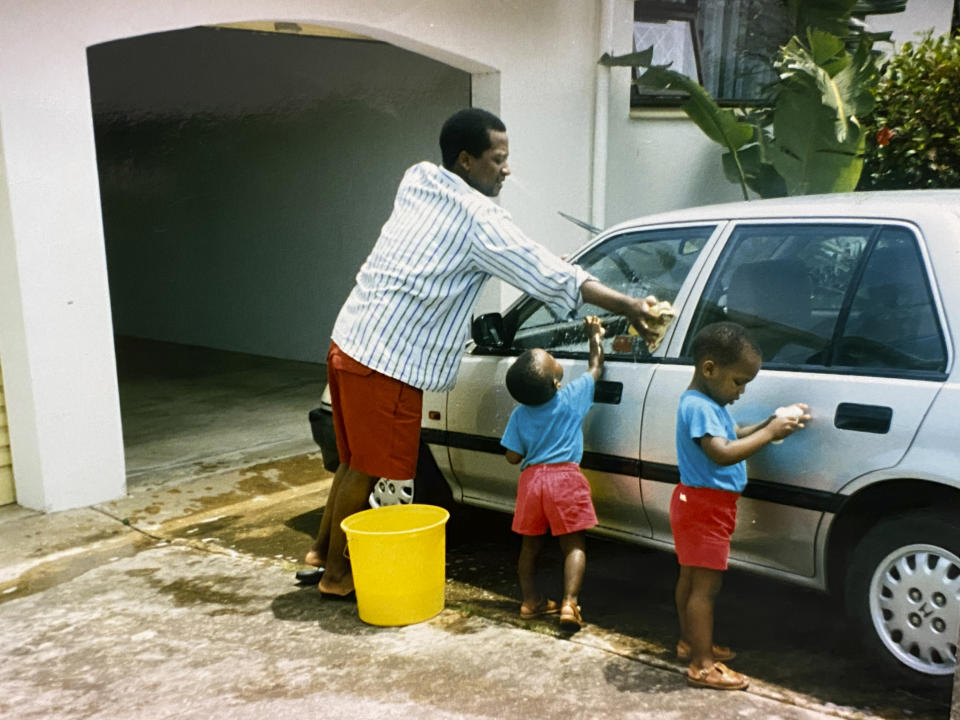 In this photo supplied courtesy of the Mini family, the late South African doctor and activist Dr. Clarence Mini, washes his car with his children in the early 1990's. Clarence Mini, a South African activist and doctor who died of COVID-19 spent his life fighting apartheid, the government's denial of HIV/AIDS and rampant corruption. Loved ones say Mini knew the odds were against him but he was committed to what he believed was right. He died in May at age 69. (Photo courtesy of the Mini family via AP)