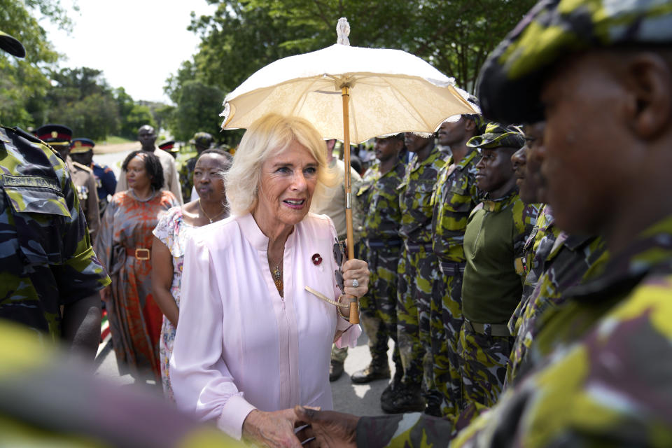 Britain's Queen Camilla holds an umbrella as she shakes hands with soldiers during her visit at the Mtongwe Naval Base in Mombasa, Kenya, Thursday, Nov. 2, 2023. (AP Photo/Brian Inganga, Pool)