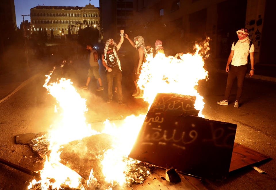Anti-government protesters chant slogans as they burn tires and woods during a protest against the political leadership they blame for the economic and financial crisis, in front the government house, in downtown Beirut, Lebanon, Thursday, June 11, 2020. (AP Photo/Hussein Malla)