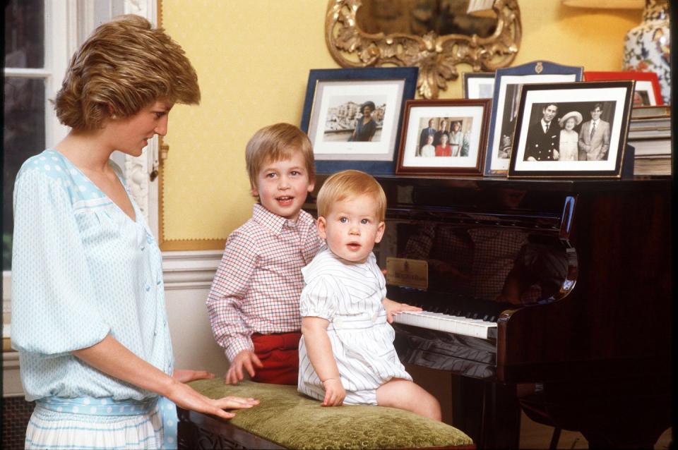 <p>Prince William and Prince Harry sit at a piano with their mother at home in Kensington Palace in 1985. </p>