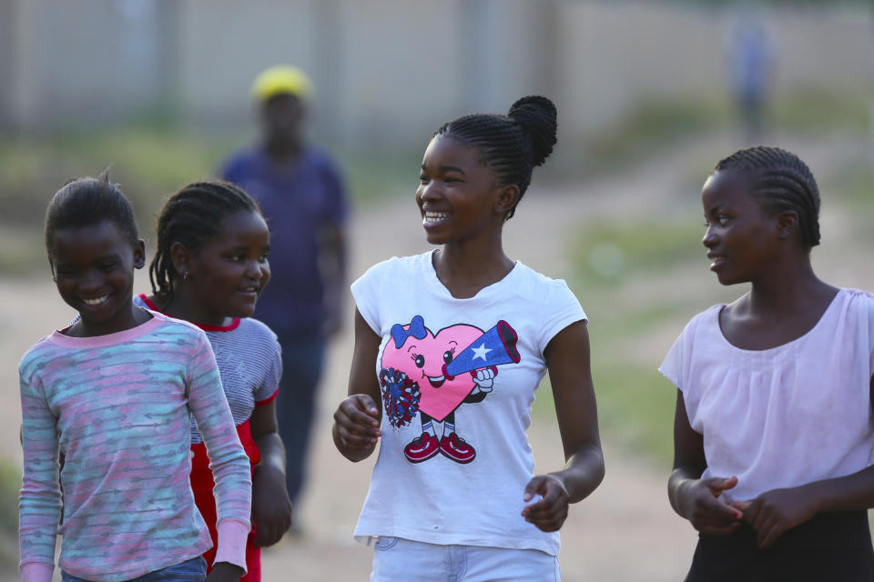 Natsiraishe Maritsa, center, shares a light moment with young boys and girls after a taekwondo training session in the Epworth settlement about 15 km southeast of the capital Harare, Saturday Nov. 7, 2020. In Zimbabwe, where girls as young as 10 are forced to marry due to poverty or traditional and religious practices, a teenage martial arts fan 17-year old Natsiraishe Maritsa is using the sport to give girls in an impoverished community a fighting chance at life. (AP Photo/Tsvangirayi Mukwazhi)
