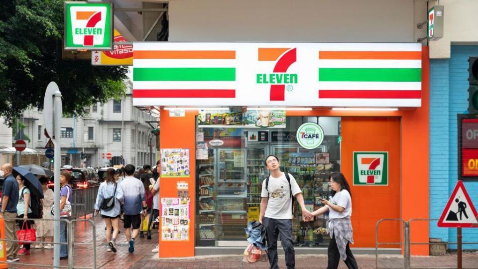 Pedestrians walk past the Japanese-owned American shop chain 7-Eleven in Hong Kong.