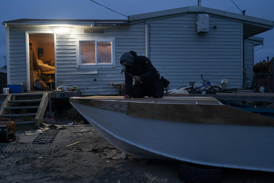 Patrick Iyatunguk, a 31-year-old seal hunter, builds his boat outside his home in Shishmaref, Alaska, Wednesday, Oct. 5, 2022. (AP Photo/Jae C. Hong)