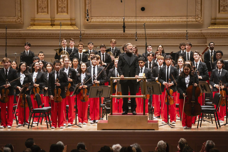 This image provided by the Carnegie Hall shows the National Youth Orchestra of the USA being led by Sir Andrew Davis. Teenaged musicians from the National Youth Orchestra of the USA walked onto the Carnegie Hall stage before rehearsal and had a uniform reaction, much like string sections following their leaders: They pulled out cell phones and took selfies. Carnegie Hall's initiative to train the next generation turned 10 this year. (Chris Lee/Carnegie Hall via AP)