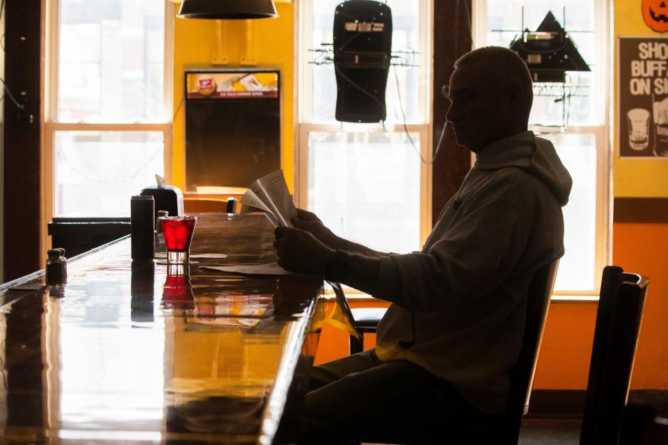 A patron reads a newspaper while waiting for lunch  at Beastro & Barley.