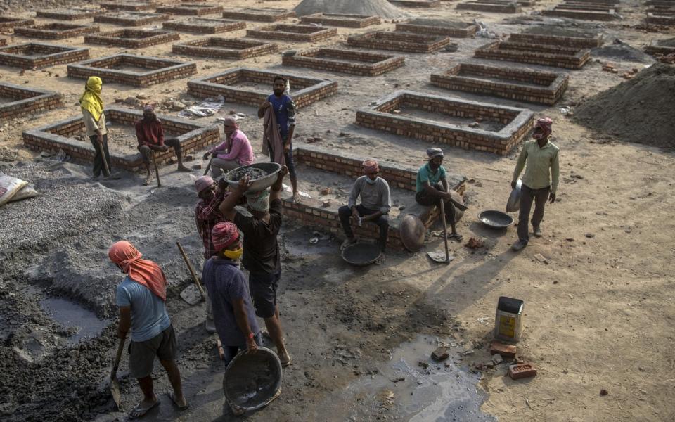 Workers constructing funeral pyre plinths at a crematorium in New Delhi - Anindito Mukherjee/Bloomberg