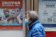 FILE PHOTO: A person walks past a poster encouraging elderly people to get vaccinated against COVID-19, in Beijing