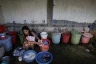 Sim Channan, de 22 años y trabajadora textil, lava la ropa sentada entre cubos de plástico, marcados con el número de habitación que tiene cada trabajador. (Reuters/Damir Sagolj).