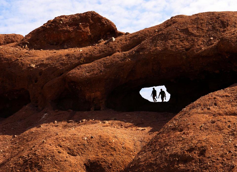 A couple walks through the Hole in the Rock during a morning hike at Papago Park in Phoenix on July 18, 2023.