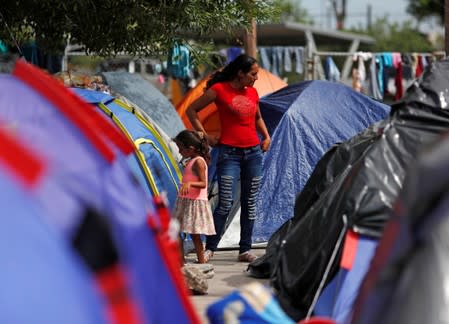 Central American migrants are seen outside their tents in an encampment in Matamoros