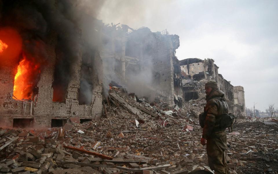 A service member of pro-Russian troops stands in front of a destroyed building in Mariupol -  CHINGIS KONDAROV/ REUTERS