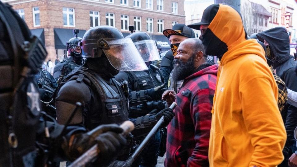 Proud Boys and other far-right protesters argue with police during a protest against COVID-19 restrictions on New Year’s Day in Salem, Oregon. Police declared the event unlawful and dispersed protesters with impact munitions and flash bang grenades after the group refused to leave downtown. (Photo by Nathan Howard/Getty Images)