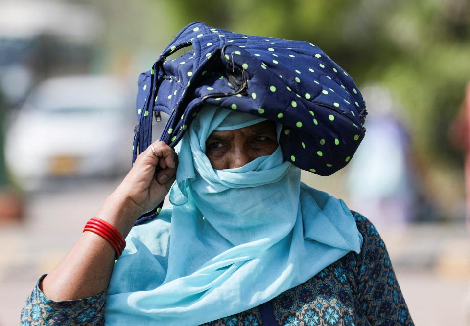 A woman uses her bag to protect herself from the sun, on a hot summer day, in New Delhi (Reuters)