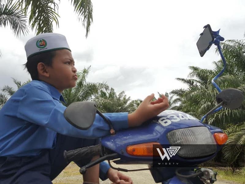 Standard Four student Muhammad Amru Umair has to go to an oil palm estate for better internet connection to participate in online classes. — Picture from Facebook/Wide TV