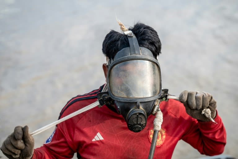 A diver in Myanmar works to recover a sunken ship in the Yangon River, plunging down to attach cables to the wreck and using the power of the tides to bring the boat to shore (Sai Aung MAIN)