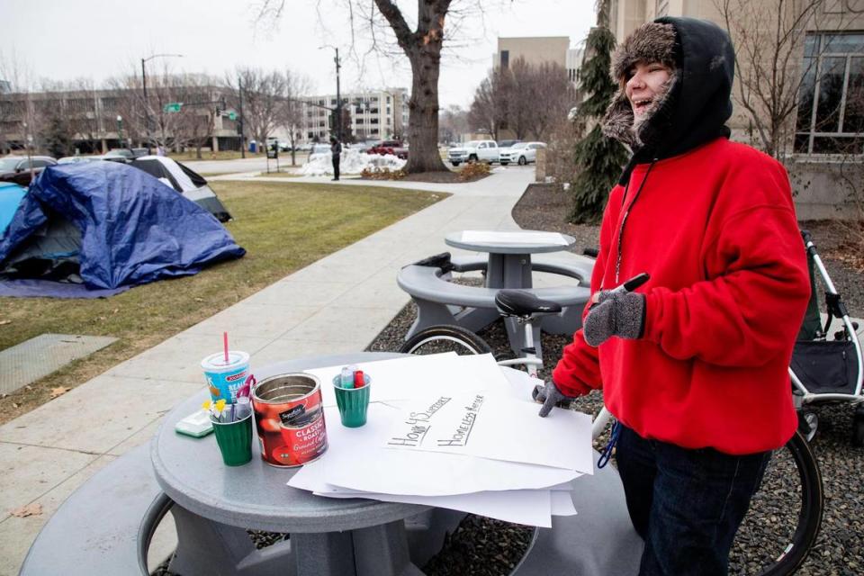 Chyann Hummer, who is experiencing homelessness, makes a sign requesting motorists to honk in support of homeless people as they pass the protest on Tuesday.