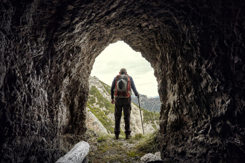 person with his back to a cave entrance