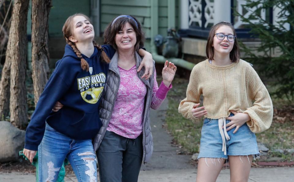 Allison Gritton, center, sings along with her daughters Jessie, left, and Jackie during a nightly 44th Street front porch sing-along in Indianapolis.