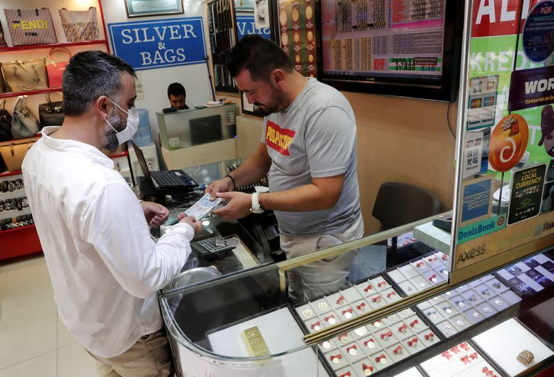 Gold dealer Gunay Gunes talks to a customer who wants to buy gold, in Istanbul