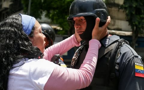 A supporter of Venezuelan opposition leader and self-proclaimed acting president Juan Guaido, holds a policeman's face during a demonstration in Caracas - Credit: AFP