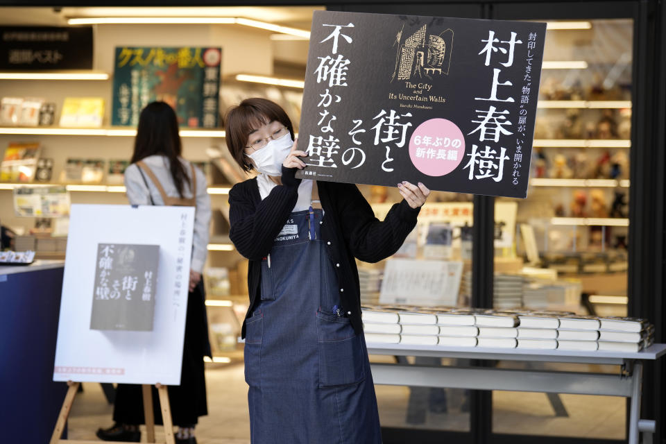 A shop clerk advertises a Japanese writer Haruki Murakami's new novel "The City and Its Uncertain Walls" on the first day for sale at Kinokuniya bookstore in Shinjuku district on early Thursday, April 13, 2023, in Tokyo. Murakami wrote a story of a walled city when he was fresh off his debut. More than four decades later, as a seasoned and acclaimed novelist, he gave it a new life as “The City and Its Uncertain Walls.”(AP Photo/Eugene Hoshiko)