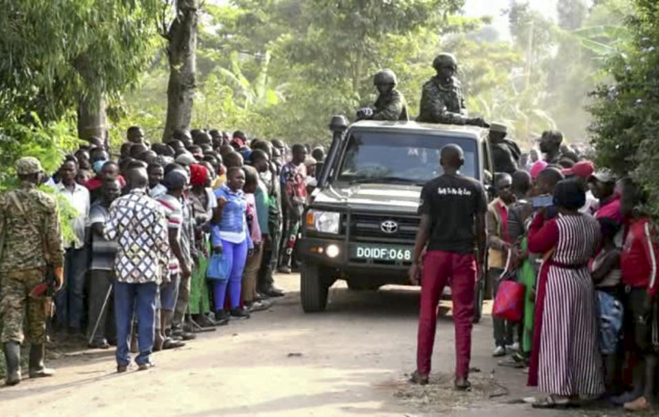 In this image made from video, security forces drive past a crowd of people gathered outside the Lhubiriha Secondary School following an attack on the school near the border with Congo, in Mpondwe, Uganda, Saturday, June 17, 2023. Ugandan authorities recovered the bodies of dozens of people including students who were burned, shot or hacked to death after suspected rebels attacked the school, the local mayor said Saturday. (AP Photo)