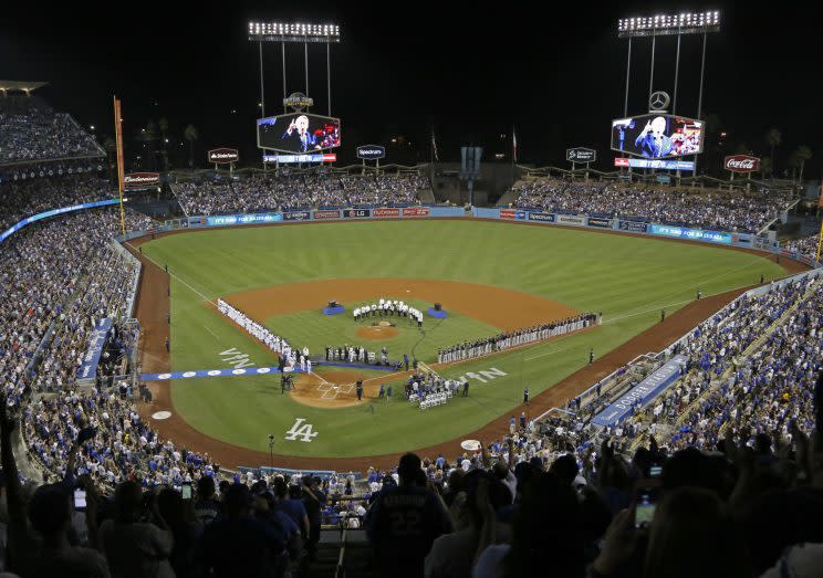 Both teams stand on the baselines as the members of the Los Angeles Philharmonic, under the direction of famed composer John Williams, prepare to play the national anthem as Los Angeles Dodgers Hall of Fame broadcaster Vin Scully is honored in a ceremony before a baseball game against the Colorado Rockies at Dodger Stadium Friday, Sept. 23, 2016. (AP Photo/Reed Saxon)