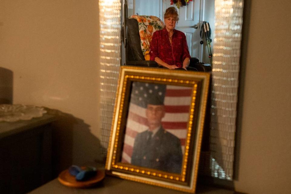 Deborah Tainsh, an author and gold star mother, is reflected in a mirror above a photo of her son Patrick, at her home in Biloxi on Wednesday, Nov. 8, 2023. Patrick died in the war in Iraq.