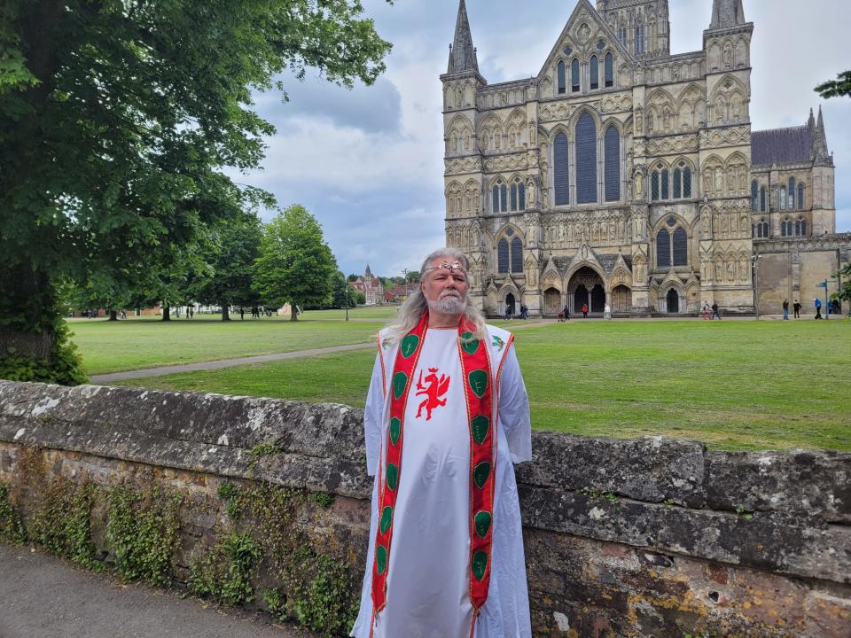 Druid dressed in traditional robe standing outside the entrance of Salisbury Cathedral