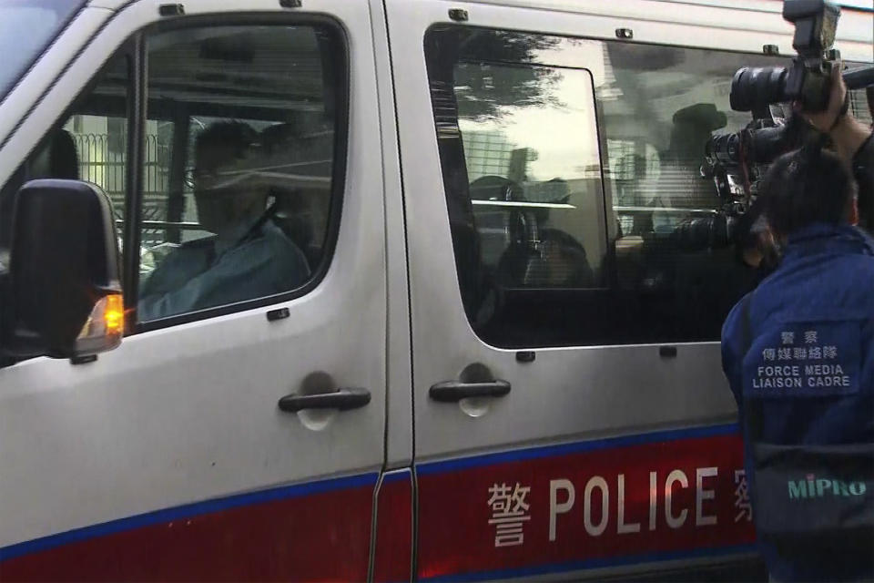 In this image taken from video footage run by TVB Hong Kong, journalists try to film a police van believed to be carrying relatives of murdered model Abby Choi on its arrival at the Kowloon City Law Courts Building in Hong Kong, Monday, Feb. 27, 2023. The ex-husband and former in-laws of a slain Hong Kong model and influencer appeared in court Monday on a joint murder charge after police found her body parts in a refrigerator. (TVB Hong Kong via AP)