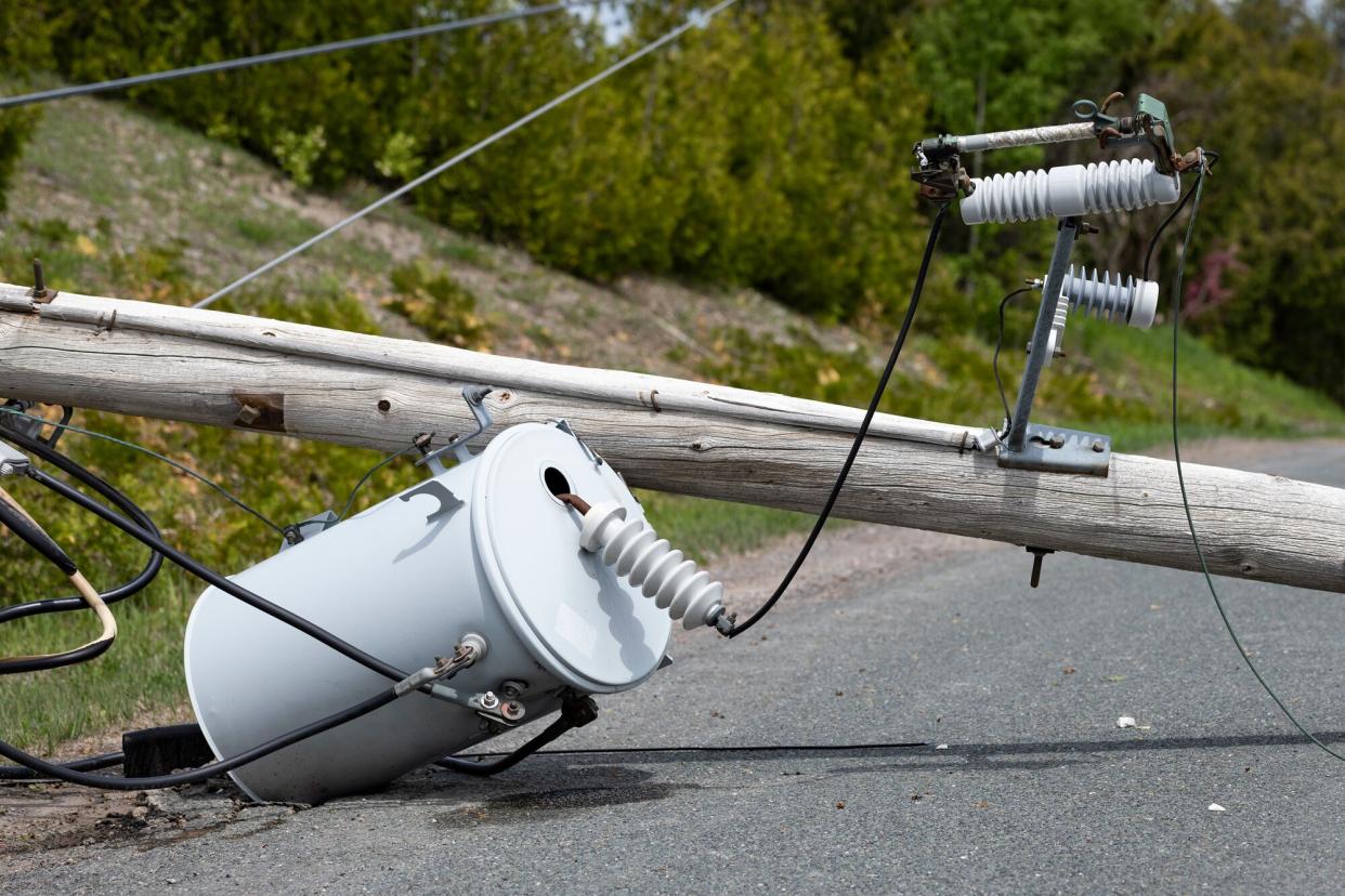 A broken power line lays across a country road. It has snapped after severe winds.