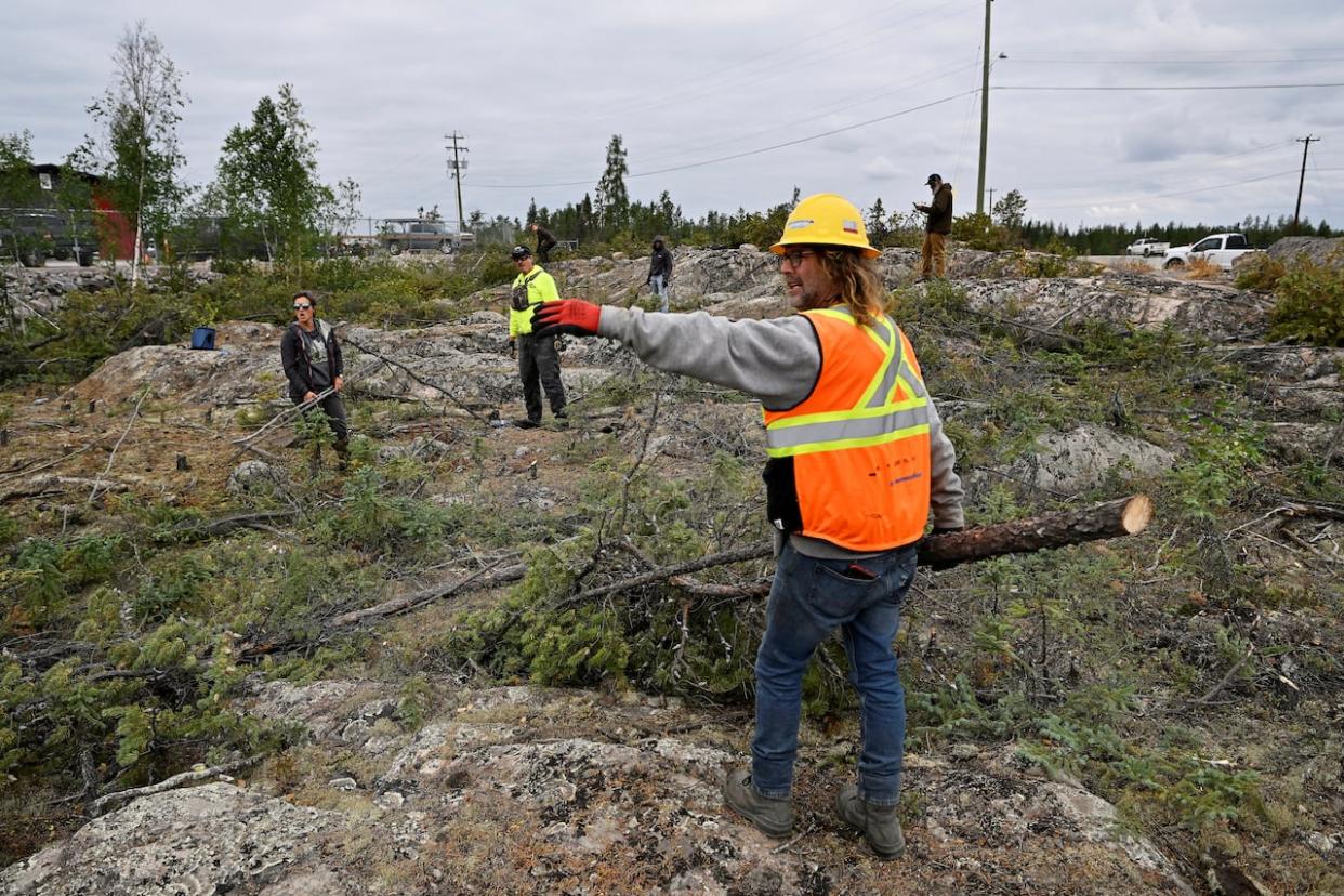 Volunteers, including Edmund Gill, up front, clear dry branches to create a firebreak as wildfires threatened the Northwest Territories town of Yellowknife in August. More than four million hectares of N.W.T. forest have burned during the 2023 fire season. (Jennifer Gauthier/Reuters - image credit)