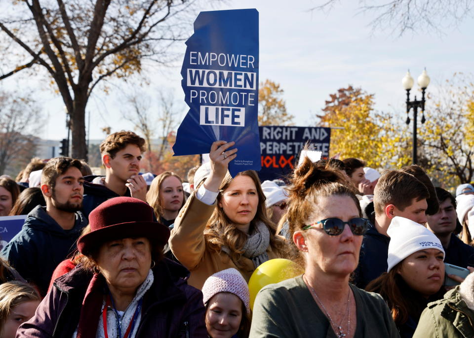 A person in a crowd holds up a sign in the shape of the state of Mississippi that reads 