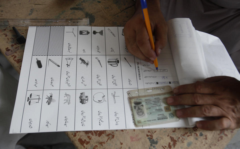 An election worker prepares ballot paper for a tribesman, waiting to cast his vote in a polling station during an election for provincial seats in Jamrud, a town of Khyber district, Pakistan, Saturday, July 20, 2019. Pakistan's northwestern tribal areas are holding their first-ever provincial elections. The seven tribal areas were merged last year as tribal districts into the northwestern Khyber Pakhtunkhwa province. Before that, the tribal areas were federally administered, and residents could only vote in the national assembly. (AP Photo/Muhammad Sajjad)