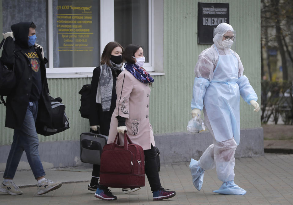 A medical worker wearing a protective suit accompanies students into an ambulance in Minsk, Belarus, Tuesday, April 21, 2020. The World Health Organization is urging the government of Belarus to cancel public events and implement measures to ensure physical and social distancing amid the growing coronavirus outbreak. (AP Photo/Sergei Grits)