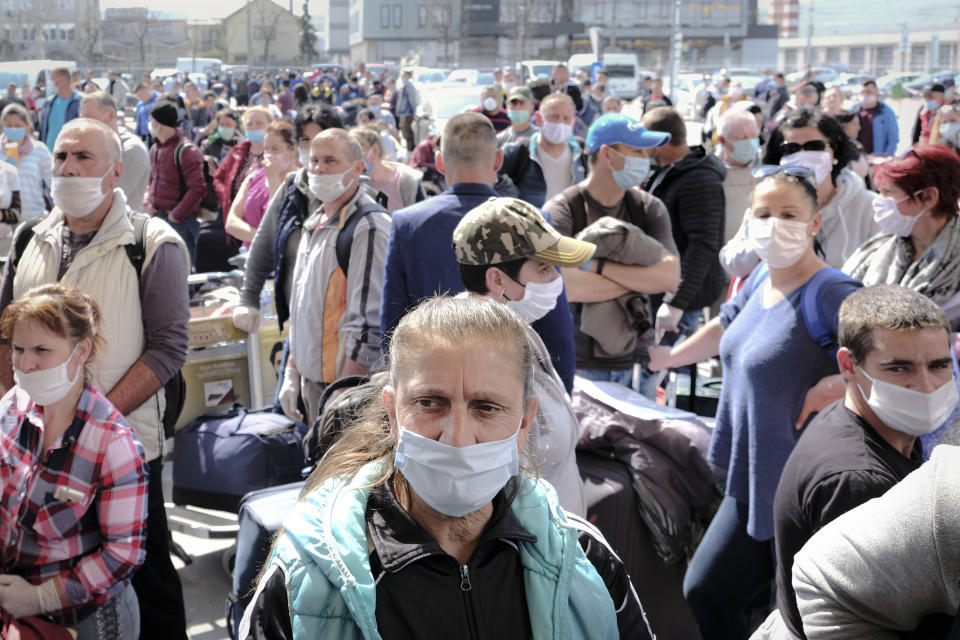 Romanian seasonal workers wait outside the Avram Iancu international airport, in Cluj, central Romania, Thursday, April 9, 2020. More then 1800 workers from across Romania are traveling on 12 flights to Berlin, Baden Bade and Dusseldorf in Germany, most of them to work in asparagus farms.(AP Photo/Raul Stef)