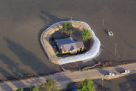 VICKSBURG, MS - MAY 18: A levee protects a home surrounded by floodwater from the Yazoo River May 18, 2011 near Vicksburg, Mississippi. The flooded Mississippi River is forcing the Yazoo River to top its banks where the two meet near Vicksburg causing towns and farms upstream on the Yazoo to flood. The Mississippi River at Vicksburg is expected to crest May 19. Heavy rains have left the ground saturated, rivers swollen, and have caused widespread flooding along the Mississippi River from Illinois to Louisiana. (Photo by Scott Olson/Getty Images)