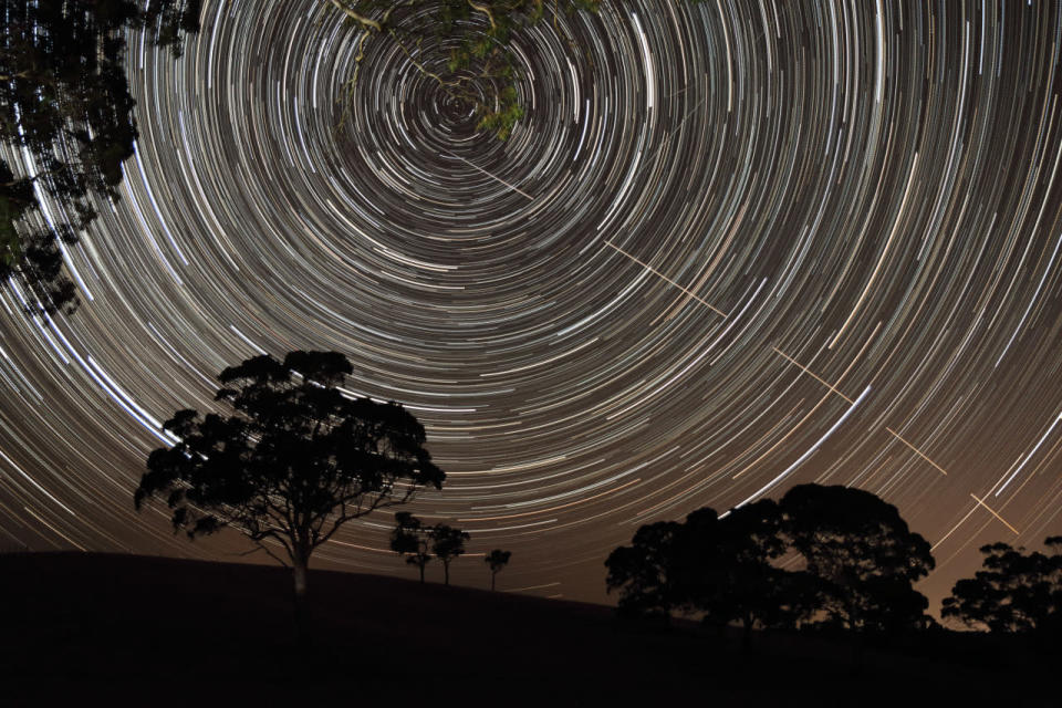 <p>The International Space Station pierces a path across concentric star trails as they spin over the trees in Harrogate, South Australia. (Scott Carnie-Bronca)</p>