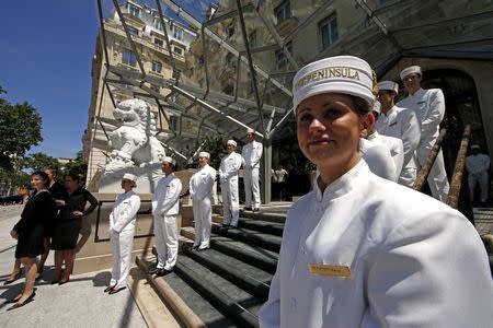 Employees pose on the steps outside the Peninsula Paris luxury hotel during a press presentation in Paris in this June 24, 2014 file picture. REUTERS/Benoit Tessier/Files