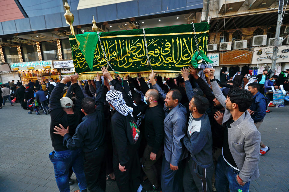 Shiite worshippers carry a symbolic coffin at the golden-domed shrine of Imam Moussa al-Kadhim, who died at the end of the 8th century, during the annual commemoration of his death, in Baghdad, Iraq, Wednesday, March 10, 2021. (AP Photo/Hadi Mizban)