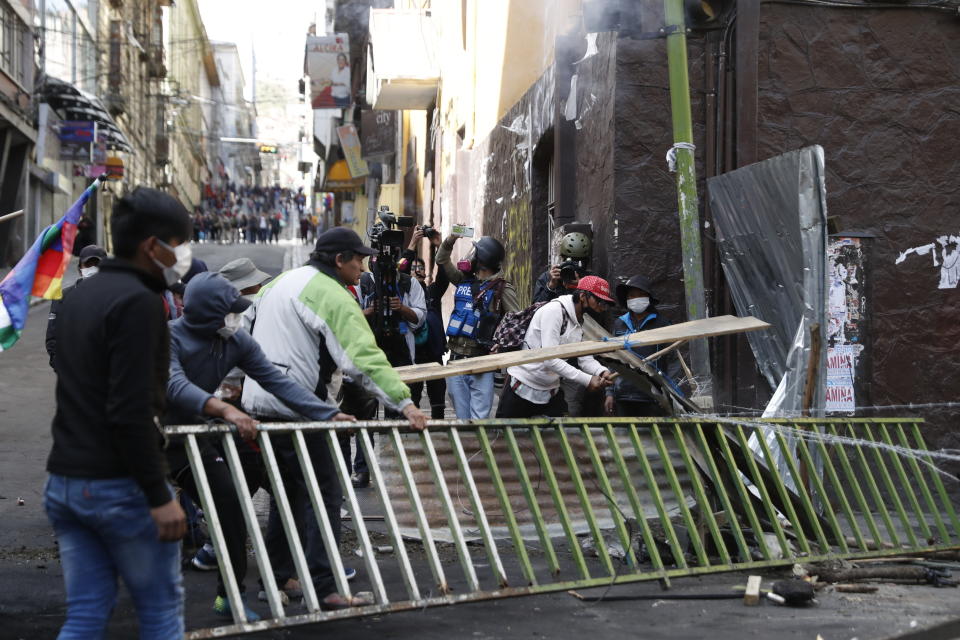 Supporters of former President Evo Morales bring down a barricade that was keeping them from reaching the presidential palace, during clashes with police in La Paz, Bolivia, Friday, Nov. 15, 2019. Morales stepped down on Sunday following nationwide protests over suspected vote-rigging in an Oct. 20 election in which he claimed to have won a fourth term in office. An Organization of American States audit of the vote found widespread irregularities. (AP Photo/Natacha Pisarenko)