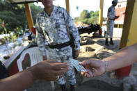 A Mexican National Guardsman checks the identification card of a man near the Suchiate River in Ciudad Hidalgo, on the Mexican border with Guatemala, Sunday, Jan. 19, 2020. Mexican authorities have closed a border entry point in southern Mexico after thousands of Central American migrants tried to push across a bridge between Mexico and Guatemala. (AP Photo / Marco Ugarte)