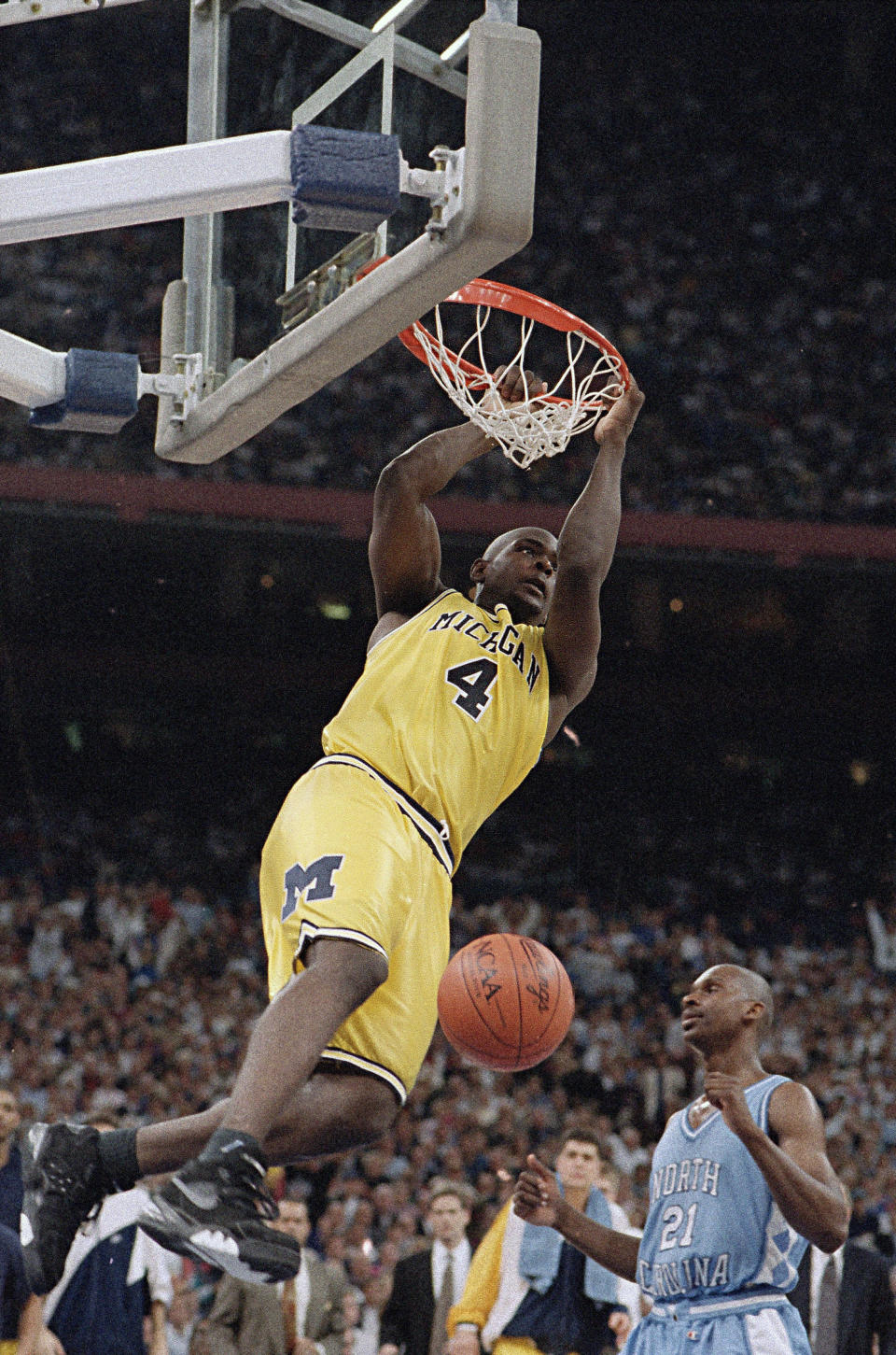 FILE - In this April 5, 1993, file photo, Michigan's Chris Webber hangs from the rim after dunking the ball during the NCAA Final Four championship game against North Carolina at the Superdome in New Orleans. North Carolina defeated Michigan, 77-71. (AP Photo/Ed Reinke, File)