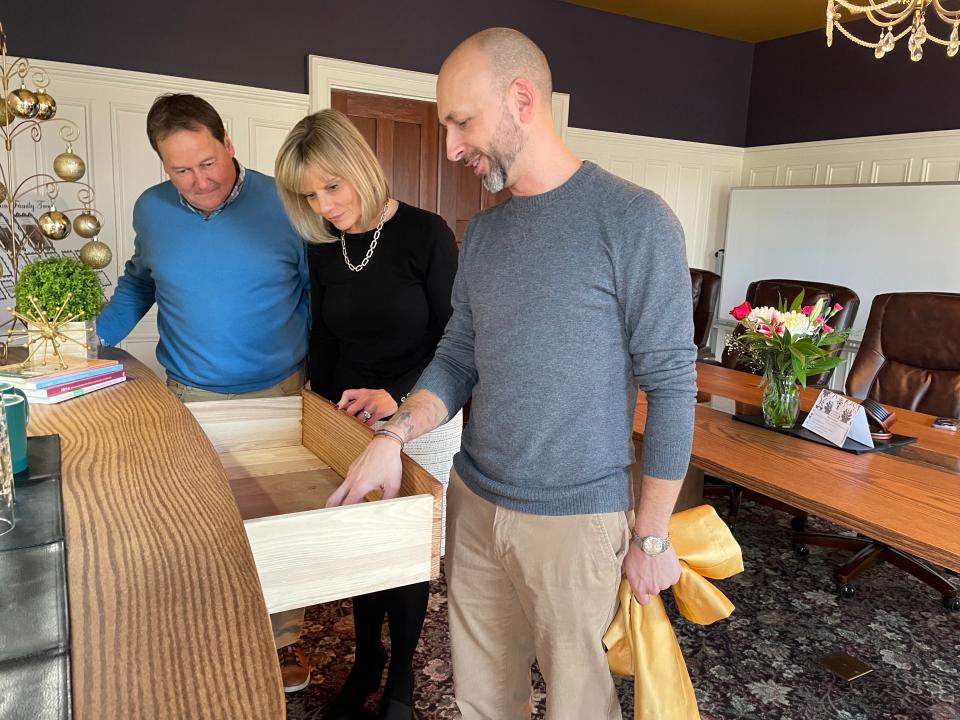 Roger and Kelly Myers inspect the details of a new buffet woodworker Garrett Roberson created out of a fallen red oak Thursday, Dec. 14, 2023.