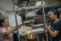 Lee Johnson, center, works in the kitchen of the restaurant, MontAsia, he runs with his wife, Yokie, left, as their daughter, Rose, 15, helps out in Fishtail, Mont., Friday, June 17, 2022. A key bridge that leads to the tourist town collapsed, causing traffic to divert through a single-lane county road. Johnson says the limited access is costing them dearly. "When we opened for the first time after the flood, it started just dead. And you start to have that sense of dread creep in. Did I do all this, did I sink all this money in, have I started this business and people can't even get here anymore?" Johnson said. (AP Photo/David Goldman)