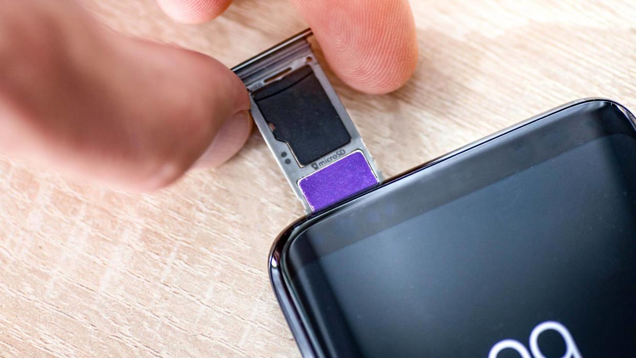  Microsd card being inserted into phone sim card tray. 