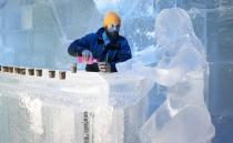 Sculptor Jonathan Bouchard of Canada poses near a sculpture at the ice bar of the Brussels Ice Magic Festival December 17, 2013. Some 20 artists from all over the world made sculptures out of 420 tonnes of ice depicting characters from comic strips. The festival will open on December 20 and will end on February 9, 2014. REUTERS/Francois Lenoir (BELGIUM - Tags: ENTERTAINMENT SOCIETY)