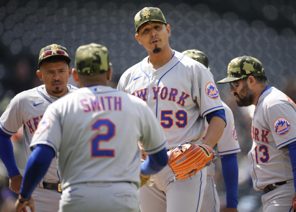 New York Mets starting pitcher Carlos Carrasco (59) is congratulated by first baseman Dominic Smith as Carrasco waits to be pulled from the mound after giving up a single to Colorado Rockies' Brendan Rodgers in the sixth inning of the first baseball game of a doubleheader, Saturday, May 21 2022, in Denver. (AP Photo/David Zalubowski)